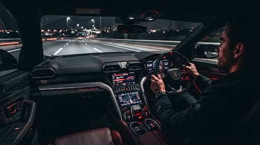 Glowing red dashboard of a supercar interior at night